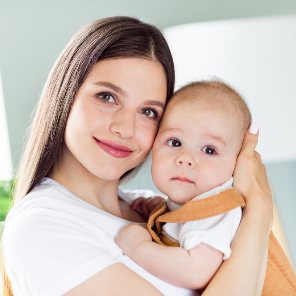 Portrait of attractive affectionate cheerful girl embracing bonding first baby nursing staying at home house indoors