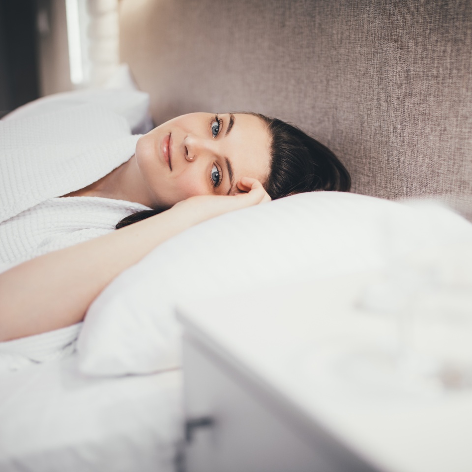Young woman sleeping in her bed with white linen at home.
