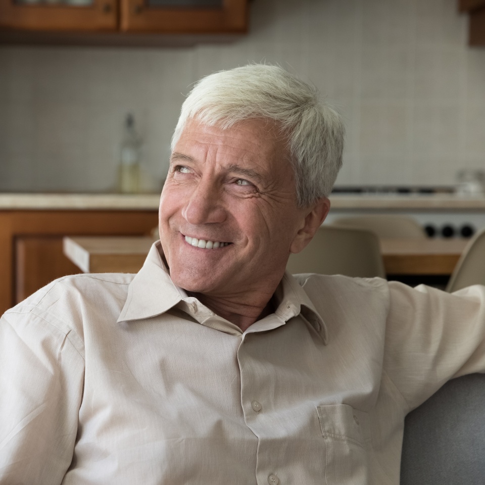 Happy old 60s man looking in distance, lost in positive thoughts. Joyful male senior pensioner recollecting good memories, dreaming or meditating alone at home, enjoying peaceful moment indoors.