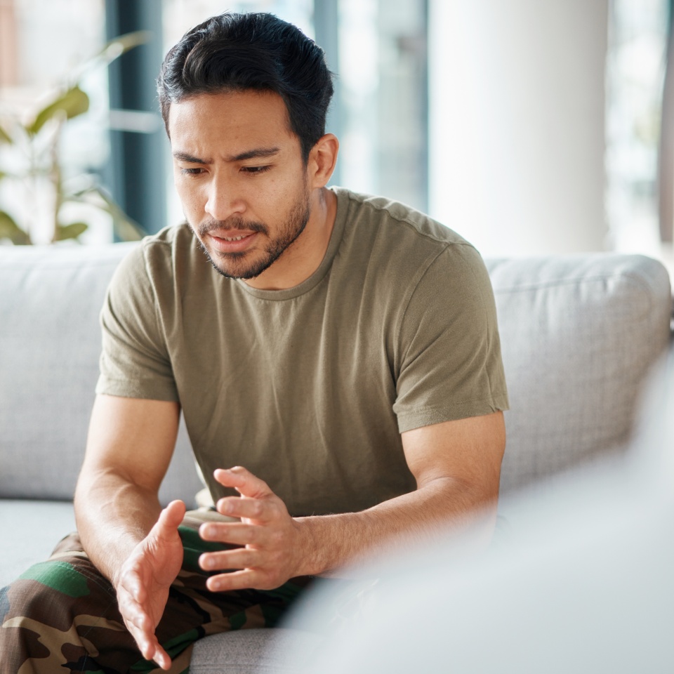 PTSD, soldier and man in therapy for trauma counseling due to military war and talking army mental health support. Consultation, depression and sad man with help for psychology problem on a sofa