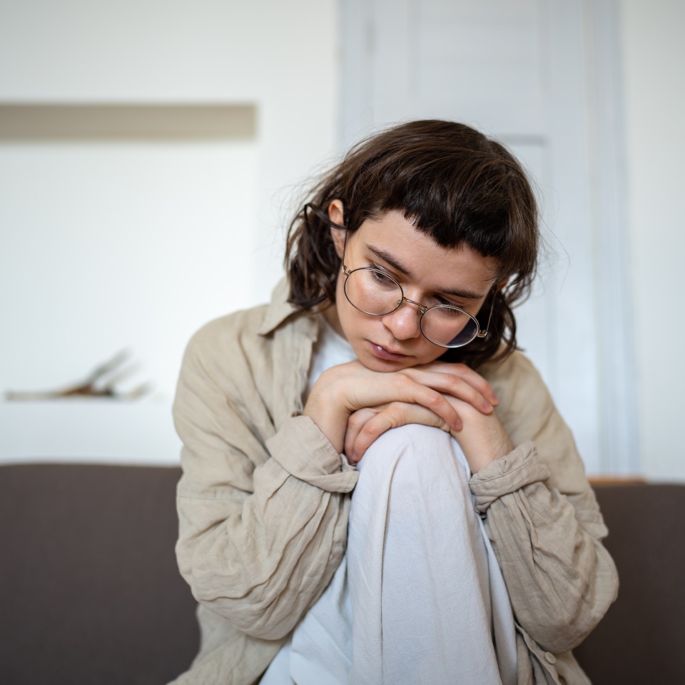 Tired depressed desperate tired teen girl sadly sitting on couch at home. Upset teenager boring. Nervous schoolgirl feels frustration hiding from society in loneliness solitude. Psychological problem