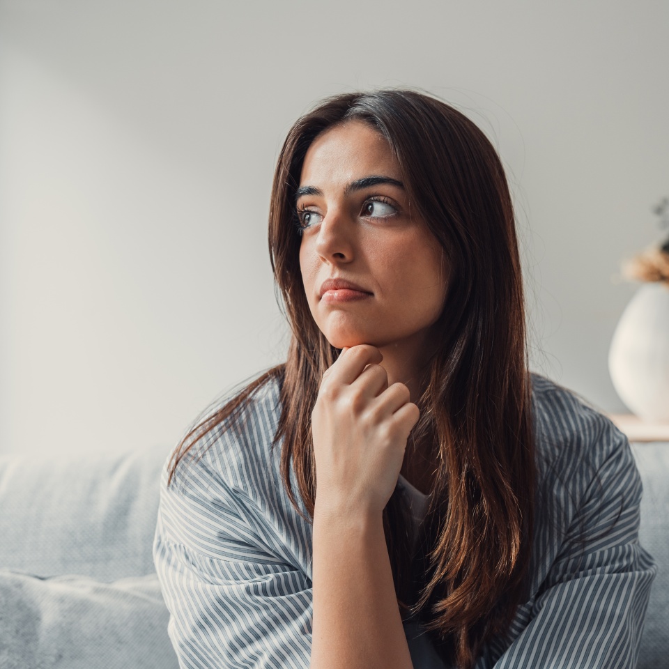 Close up of sad pensive millennial woman sit alone thinking about relationships personal problems, upset thoughtful young female lost in thoughts feel lonely depressed pondering or mourning at home