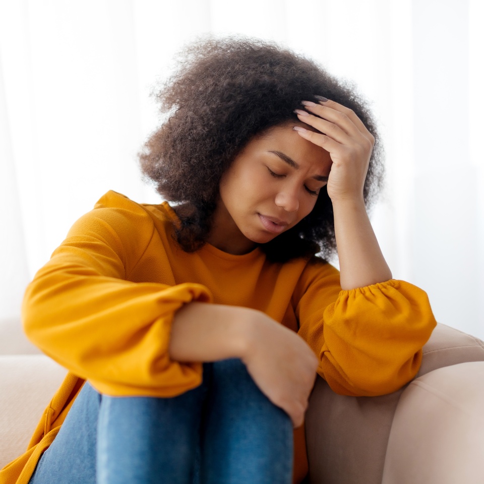 Seasonal Depression. Lonely african Woman Sitting On Couch At Home With Sad Face Expression, African Lady Having Anxiety, Feeling Tired And Bored, Staying Alone In Light Living Room, Copy Space