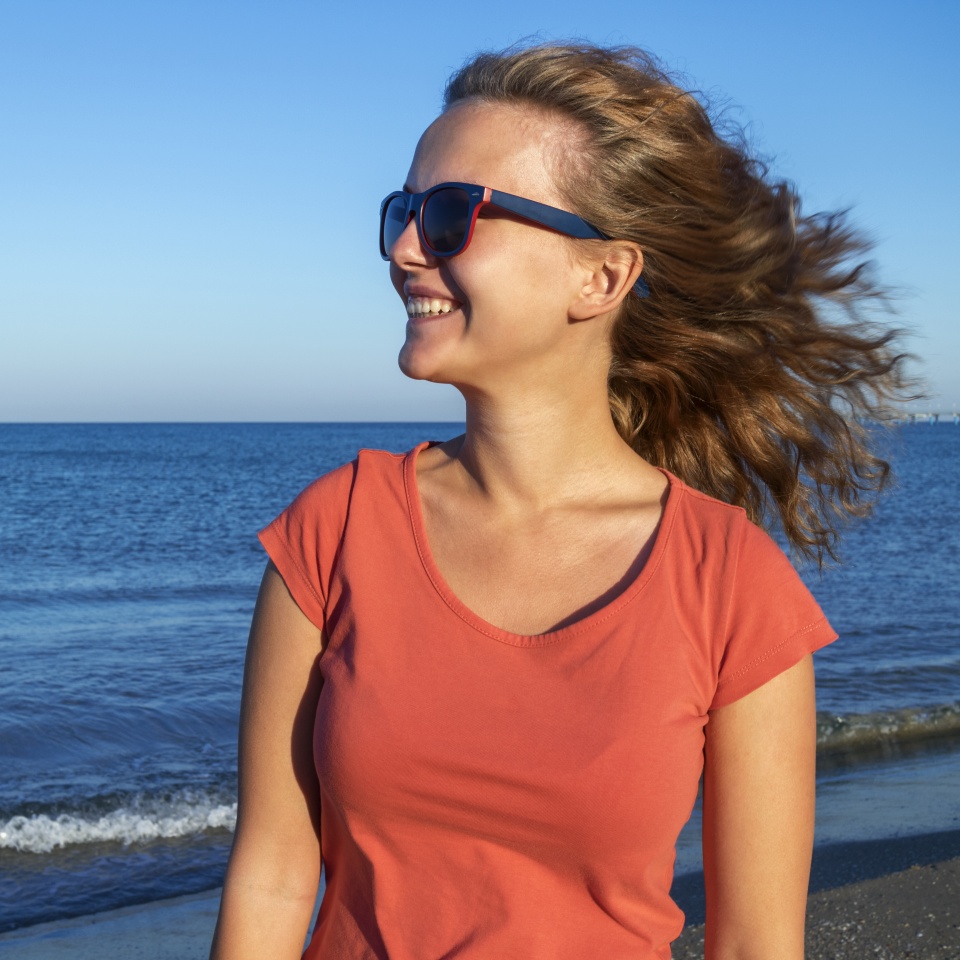 Beautiful girl smiling on the beach with the sea and blue sky