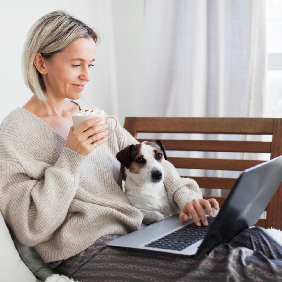 A woman uses a laptop on a couch at home while participating in a virtual mental health consultation.