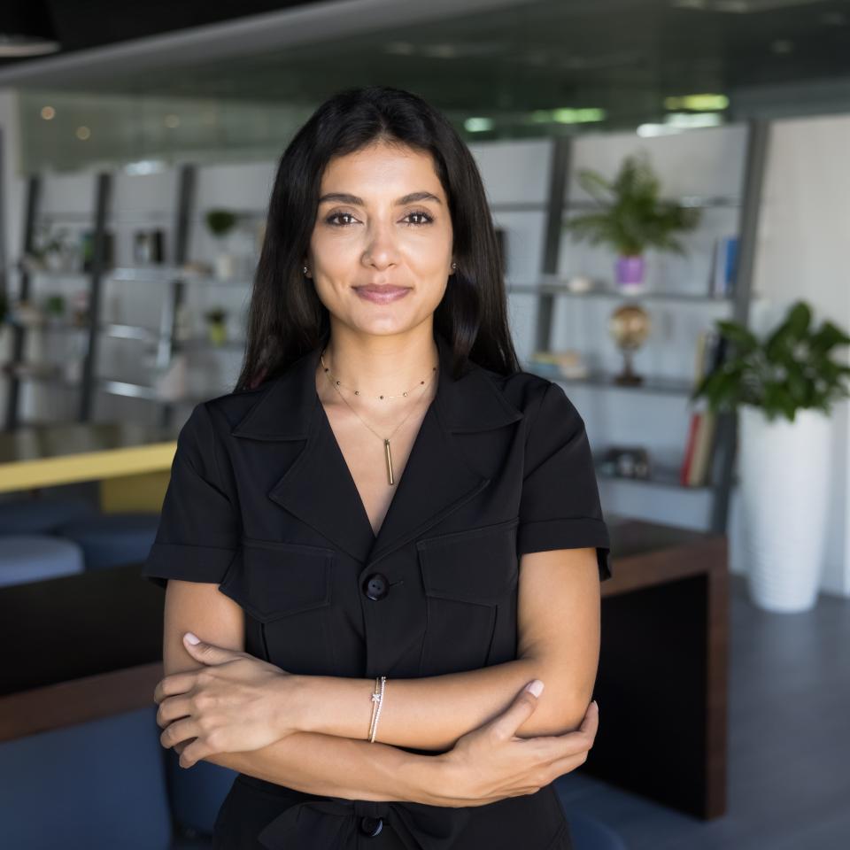 A beautiful woman with black hair, calm, standing with her hands clasped, looking at the camera – a symbol of reflection and mental balance