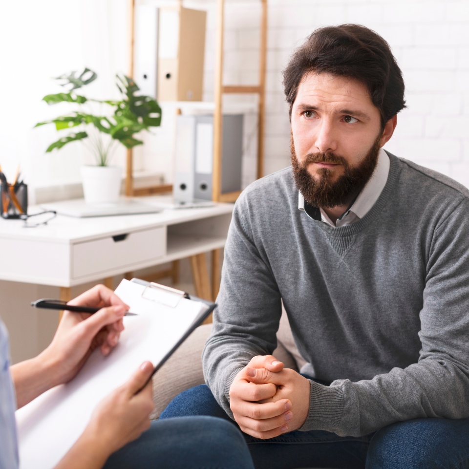 Early middle age crisis. Stressed young man talking to psychologist during individual therapy